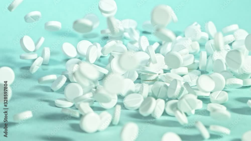 Super Slow Motion Shot of Falling White Pills on Light Green Background at 1000fps.