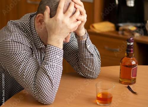 drunk man sitting at the table holding his head. photo