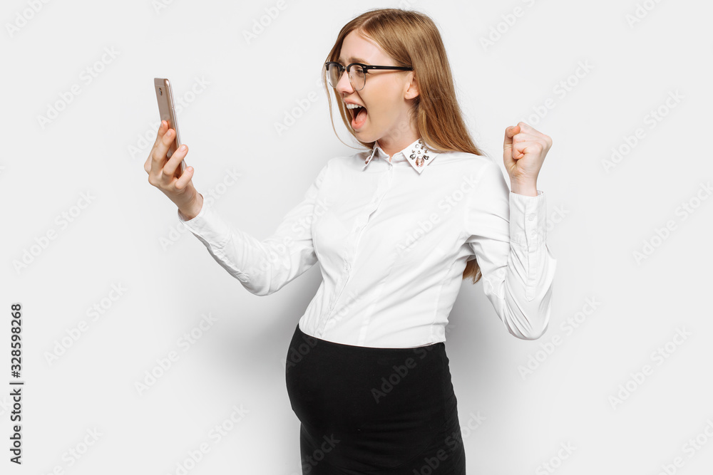 Image of a young pregnant business woman with glasses, angry and tired girl talking on the phone and shouting Image of a young pregnant business woman with glasses, angry and tired girl talking on the phone and shouting