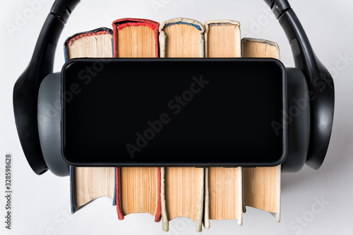 Smartphone, books and headphones close-up. White background copy space top view photo