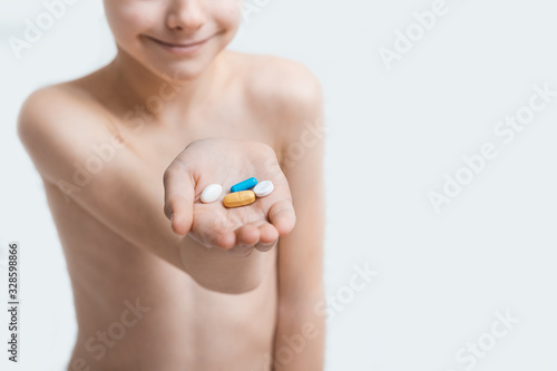 Boy child holds tablet in hands on white background. Vitamins for children