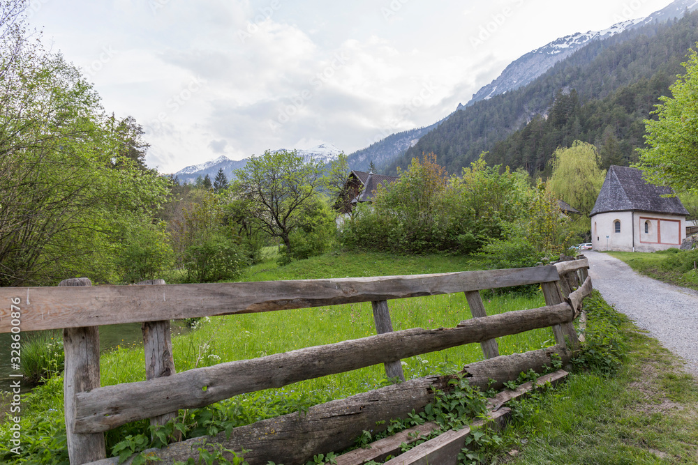 Landscape of the Alps, traditional construction with wooden fence and abundant vegetation