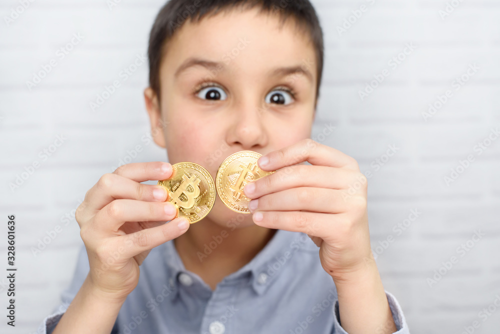 Little boy holding Bitcoin coin. Coin Focus. Child holding cryptocurrency in metal. Mining or blockchain technology. Little boy holding Bitcoin coin. Coin Focus. Child holding cryptocurrency in metal. Mining or blockchain technology.