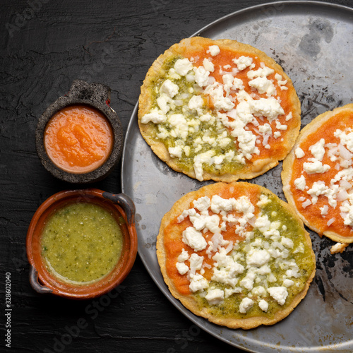 Mexican memela with green and red sauce on dark background