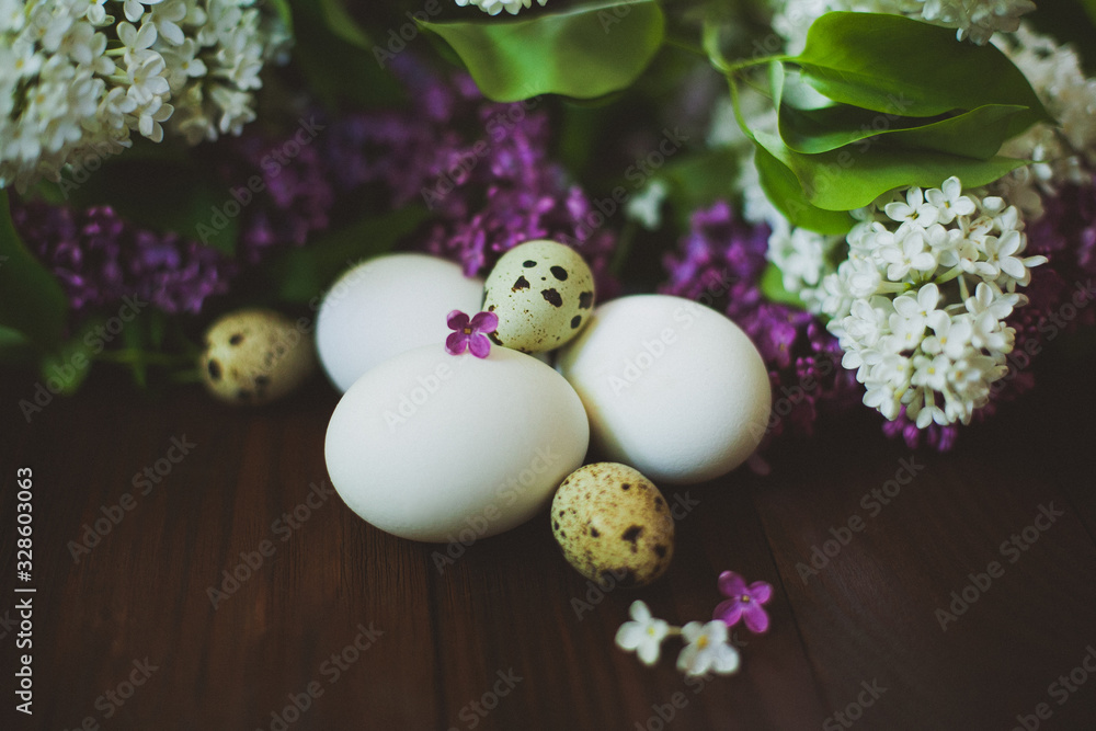 Chicken and quail eggs in a bouquet of lilac on a wooden table Chicken and quail eggs in a bouquet of lilac on a wooden table