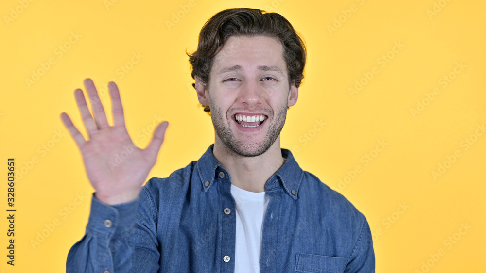 Young Man Waving and Welcoming on Yellow Background Young Man Waving and Welcoming on Yellow Background