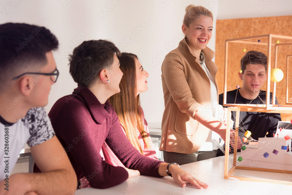 Female Architecture teacher at work. Female professor explain architectural projects to students. Beautiful female university architecture professor explain lessons to multiethnic students. Female Architecture teacher at work. Female professor explain architectural projects to students. Beautiful female university architecture professor explain lessons to multiethnic students.