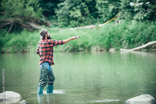 Male fishing. Man bearded fishermen. Fly fishing adventures. Rural getaway. Man fisherman catches a fish. Fishing on river. Happy cheerful human. United with nature.
