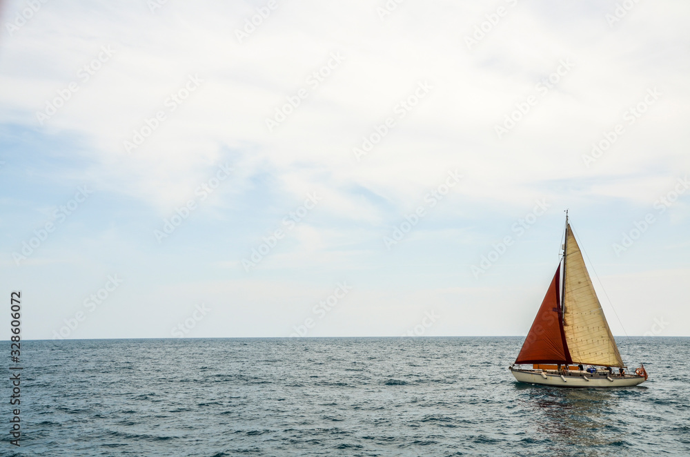 Luxury Yacht sailboat at full sail gliding through open calm blue sea waters close to the Mediterranean coast of Spain.