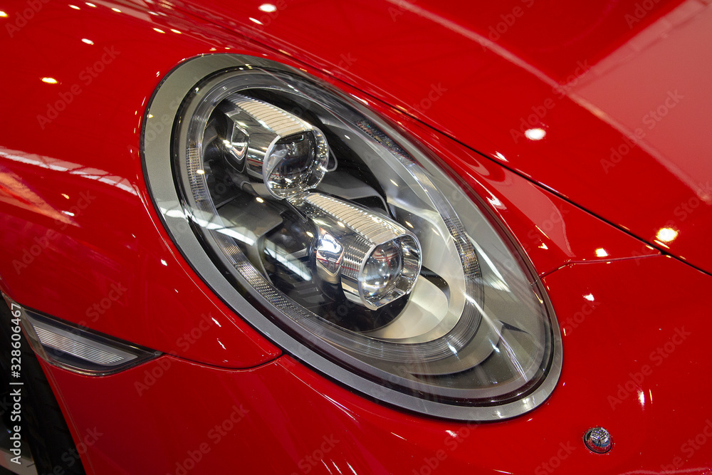 Close up shot of headlight in luxury red car background.