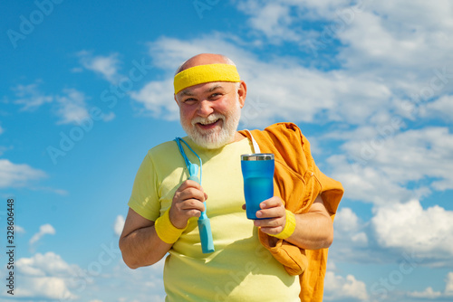Senior sport man is doing sport outdoors. Active sport workout for old person. Elderly man practicing sports on blue sky background.