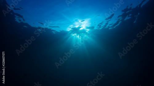 Underwater background in clear blue ocean with sunbeams 
