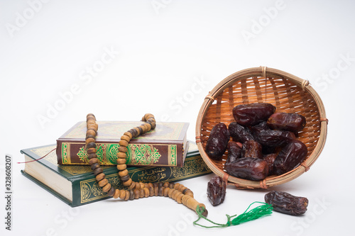 Faith in Islam concept. The Islamic holy book, Quran or Kuran, with rosary beads or “tasbih” and dates (kurma)  isolated on white background. photo