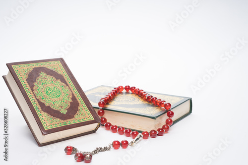Faith in Islam concept. The Islamic holy book, Quran or Kuran, with rosary beads or “tasbih” isolated on white background.