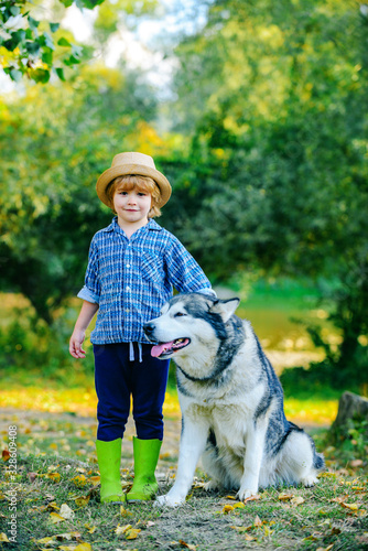 Little boy with dog walk together on green hill. Summer portrait of happy cute kid - son with dog pet. Little brother walk with puppy. Childhood memories.