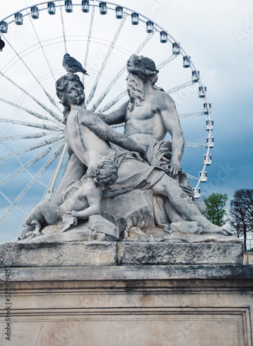 Paris touristic square with garden, sculpture and big ferris wheel on cloudy sky