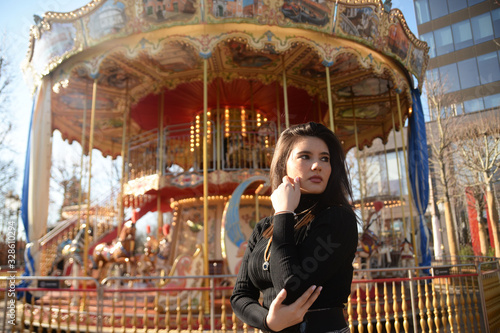 Portrait of a beautiful young woman near a carousel