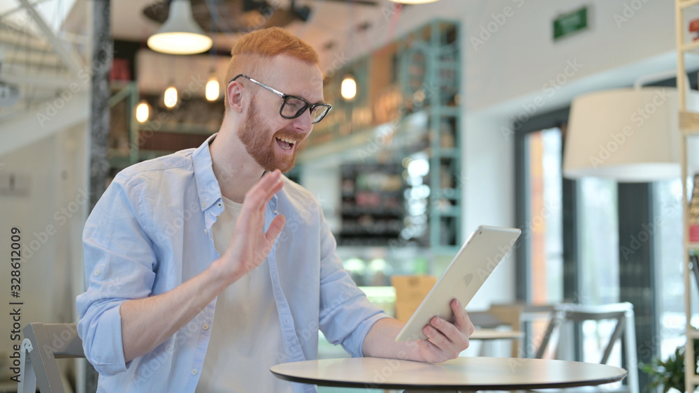 Redhead Man doing Video Chat on Tablet in Cafe Redhead Man doing Video Chat on Tablet in Cafe