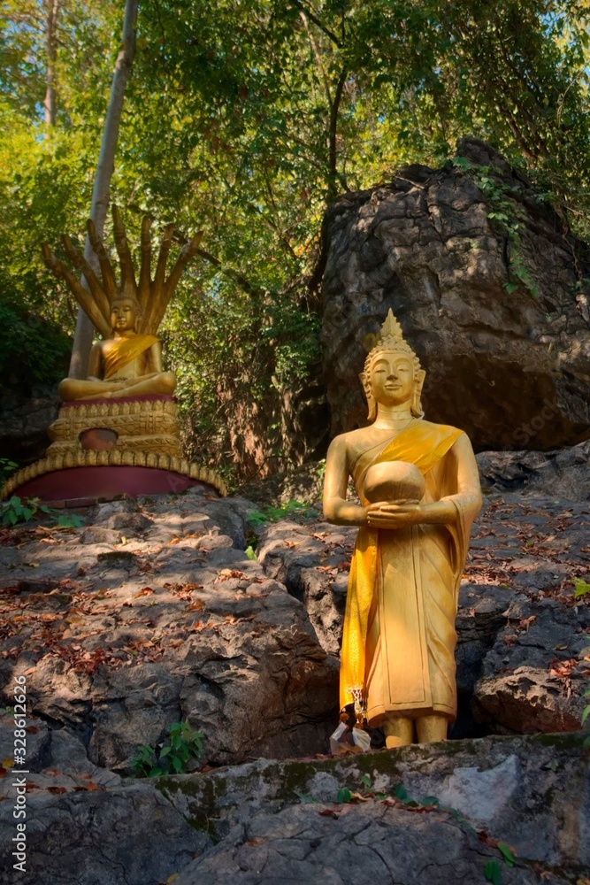 Golden statues of Buddha in the jungle, on the way to the summit of Mt Phou Si, a sacred mountain located in Luang Prabang, Laos.