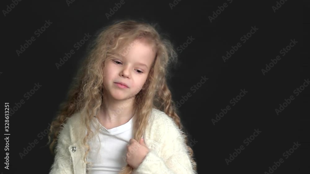 Little girl with blond curly hair, white shirt and white knitted jacket Little girl with blond curly hair, white shirt and white knitted jacket