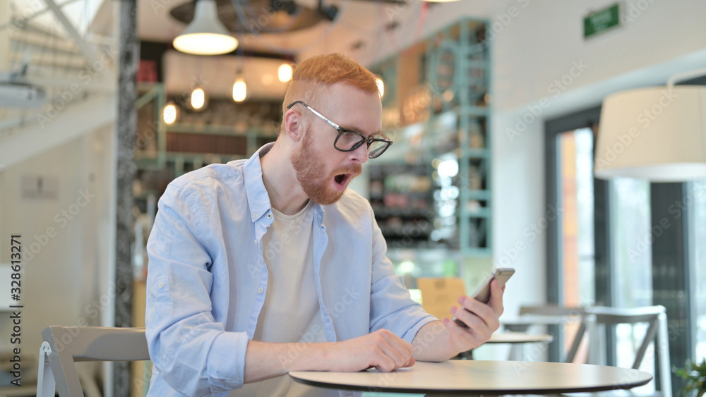 Redhead Man Reacting to Loss on Phone in Cafe Redhead Man Reacting to Loss on Phone in Cafe
