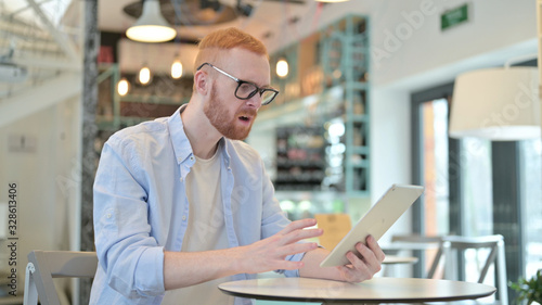 Redhead Man Shocked by Loss on Tablet in Cafe