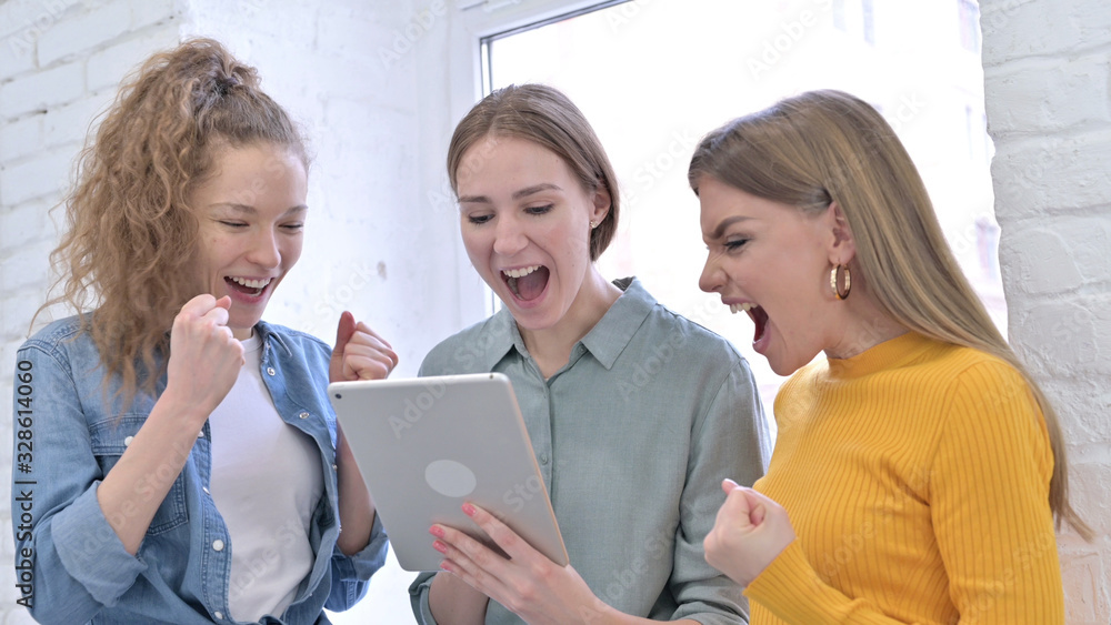 Young Creative Women Celebrating Success on Tablet Young Creative Women Celebrating Success on Tablet