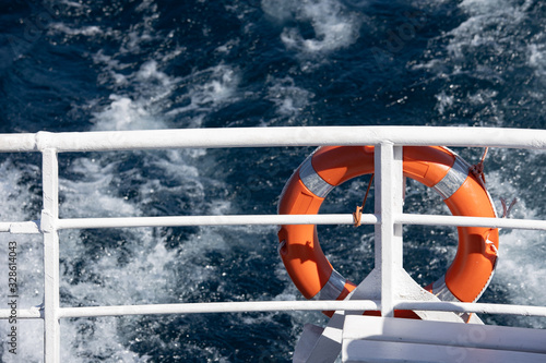 Red lifeguard on stern rail boat with swell in the background