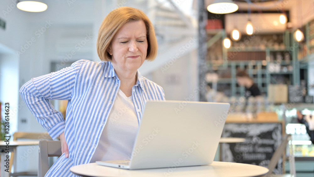 Creative Old Woman with Back Pain using Laptop in Cafe Creative Old Woman with Back Pain using Laptop in Cafe