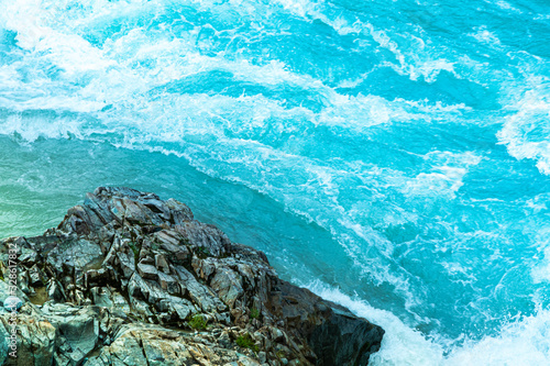 blue seething water beats against rocks, sea surf, rapid flow of  mountain river, ocean waves of tide