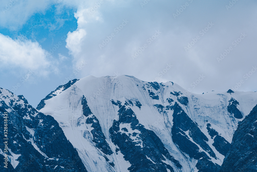 Mountain range under cloudy sky. Snowy peaks of mountains rocks Mountain range under cloudy sky. Snowy peaks of mountains rocks