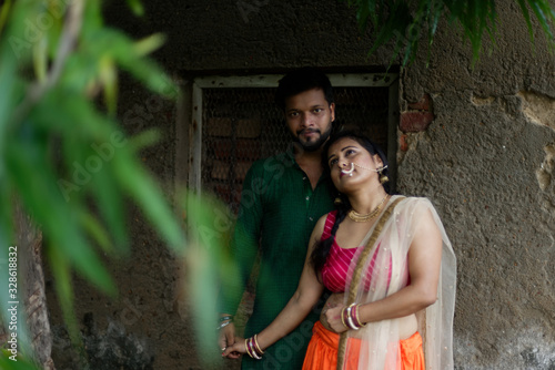 Young and attractive Indian Bengali brunette couple standing in front of a vintage house hugging each other romantically wearing Indian traditional ethnic cloths. Indian lifestyle and fashion