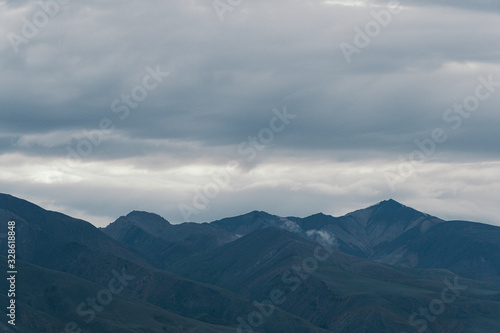 mountain valley under cloudy sky, rock ridge on horizon, hiking in mountains, rest and meditation in nature
