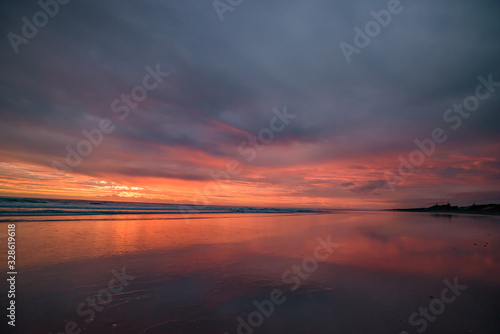 Muriwai Beach at sunset time with colorful clouds, New Zealand