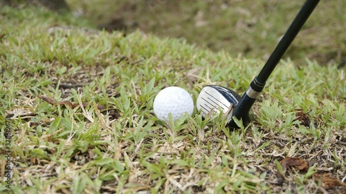 golf ball and hybrid club on green grass