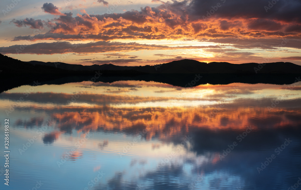 Beautiful reflection of a bright sunset in the lake. Rest in the wild.