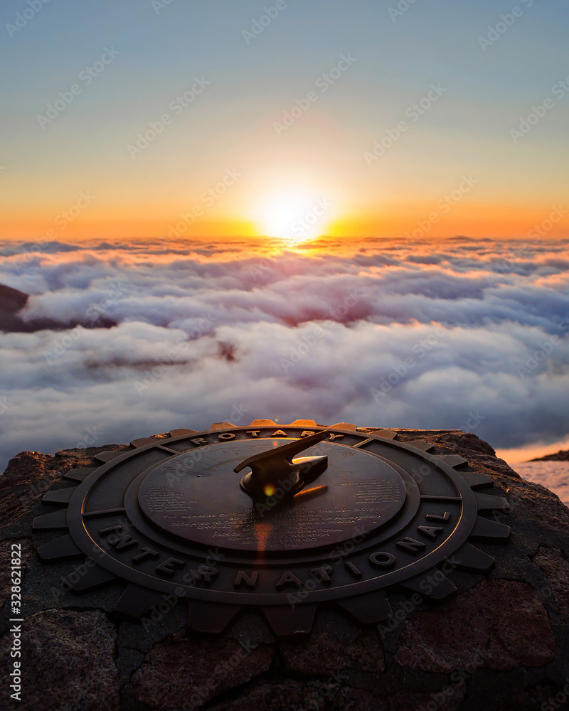 Sundial on top of a cloudy mountain during the sunrise