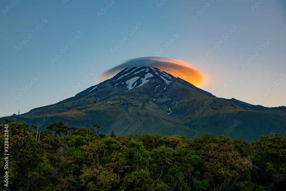 Lenticular clouds with the light of sunrise above Mount Taranaki in New Plymouth, New Zealand Lenticular clouds with the light of sunrise above Mount Taranaki in New Plymouth, New Zealand