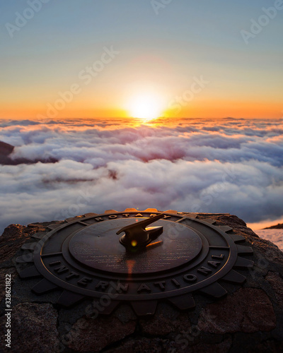 Sundial on top of a cloudy mountain during the sunrise