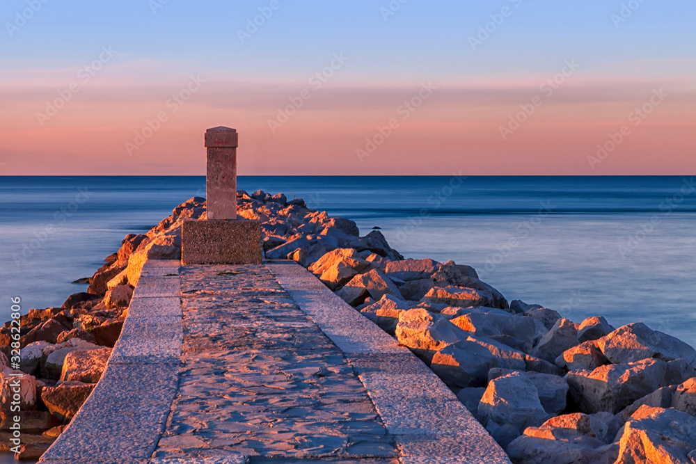 Obraz premium Alba sul mare con obelisco e rocce. Laguna di Grado provincia di gorizia. Italia. Isola del sole.