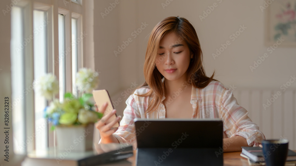 Close up view of college girl working on her assignment with tablet, smartphone and stationery on wooden table Close up view of college girl working on her assignment with tablet, smartphone and stationery on wooden table