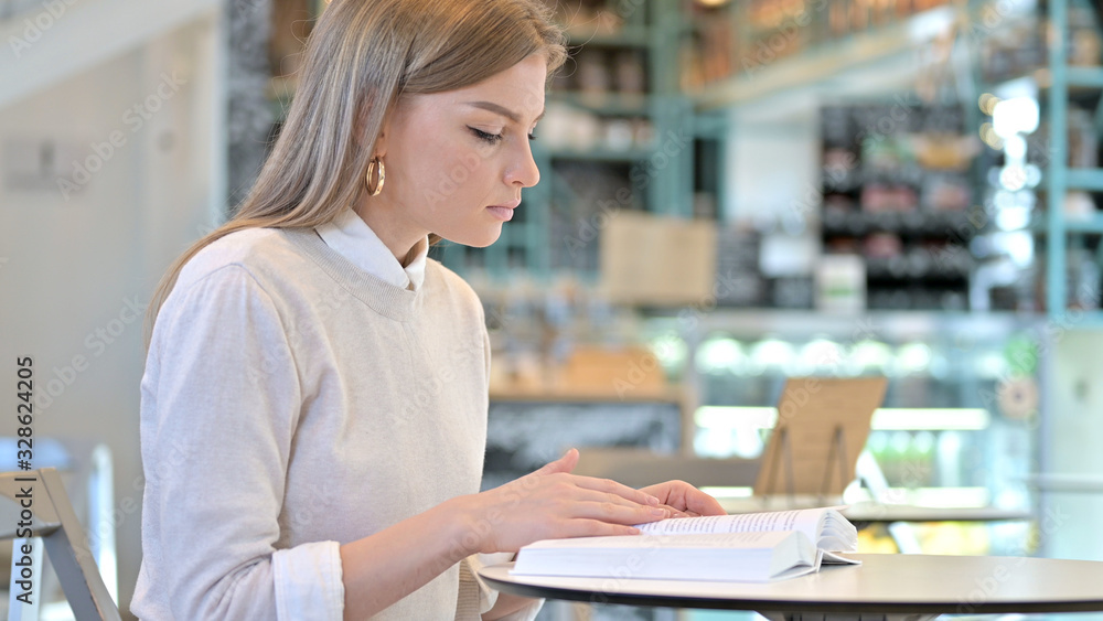 Studious Young Woman Reading Book in Cafe Studious Young Woman Reading Book in Cafe