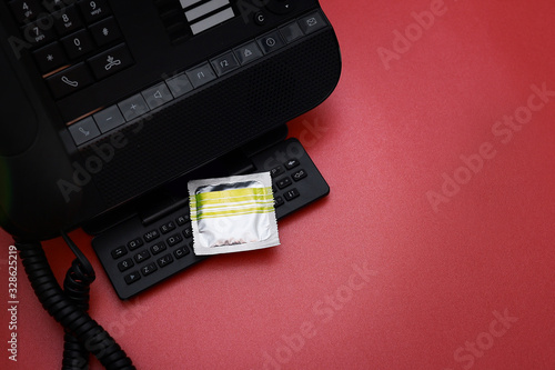 A pack of condom on the phone isolated on red background. A conceptual idea on sex business