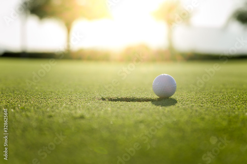 Golf club and ball in grass at the Golf course. White Golf ball on Green field golf course in morning time with sun light
