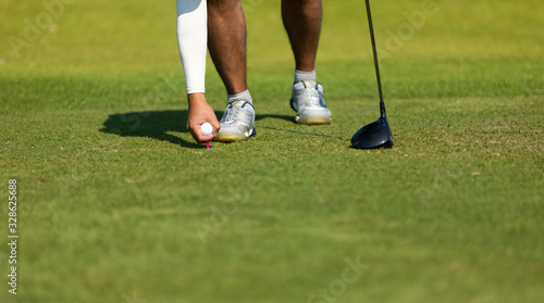 Golf club and ball in grass at the Golf course. White Golf ball on Green field golf course in morning time with sun light