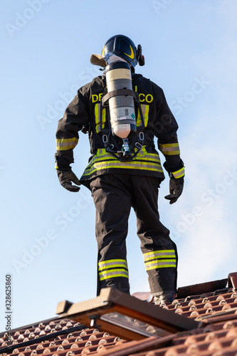 Wallpaper Mural Close up of an Italian fire fighter standing on a roof and inspecting a smoldering tile Torontodigital.ca