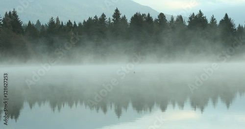 Rolling fog over calm lake in Whistler, Canada.  photo