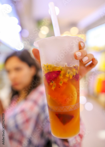 Fresh fruits in a cocktail in the hand of a girl