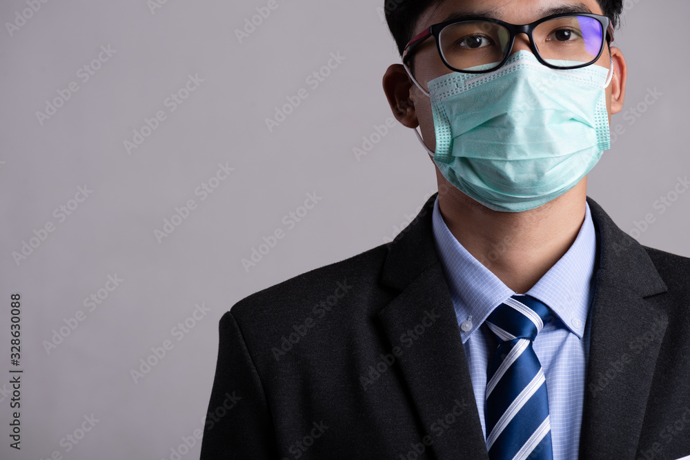 Close up of a businessman in a suit wearing Protective face mask, get ready for Coronavirus and pm 2.5 fighting against gray background. Healthcare concept. Close up of a businessman in a suit wearing Protective face mask, get ready for Coronavirus and pm 2.5 fighting against gray background. Healthcare concept.