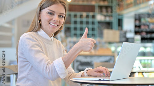 Thumbs up by Young Woman using Laptop in Cafe © stockbakers